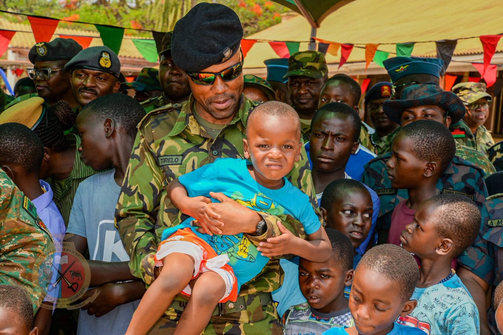 An officer carrying a little boy among the children